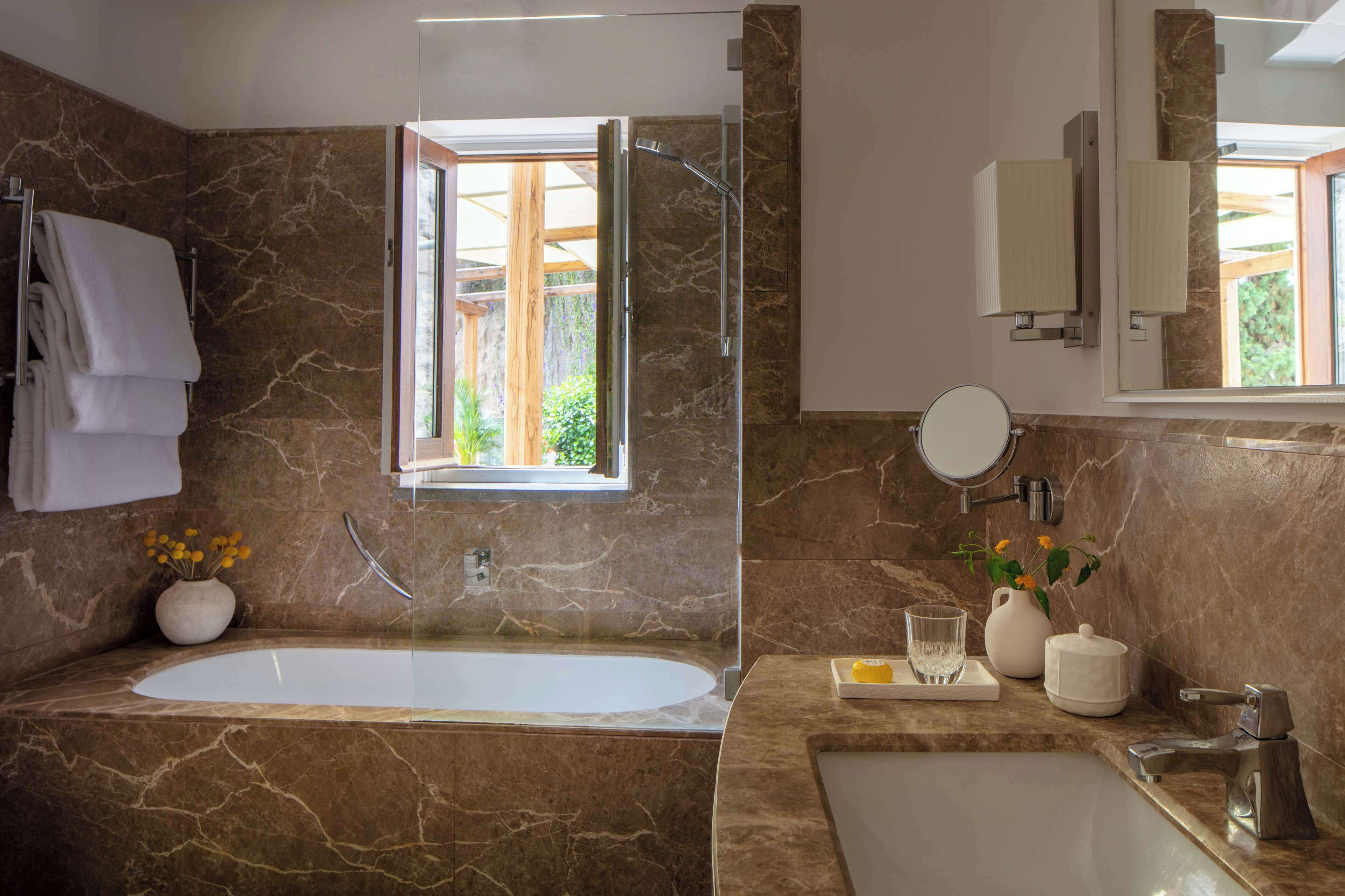 Une salle de bain avec une baignoire, un lavabo, un miroir et une fenêtre.