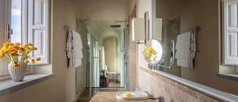 A bathroom with a large mirror, a sink, and a shower.