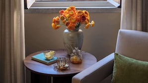 Een kamer met uitzicht op de oceaan, een vaas met bloemen op een tafel en een stoel met een kussen.