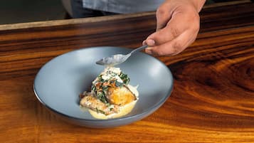 A person serving a dish on a gray plate.