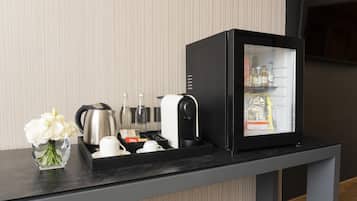Un mini-bar comprenant un réfrigérateur, une bouilloire et un vase de fleurs.