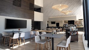 Zona de bar moderna con varias opciones de asientos, un televisor y una barra repleta de botellas.