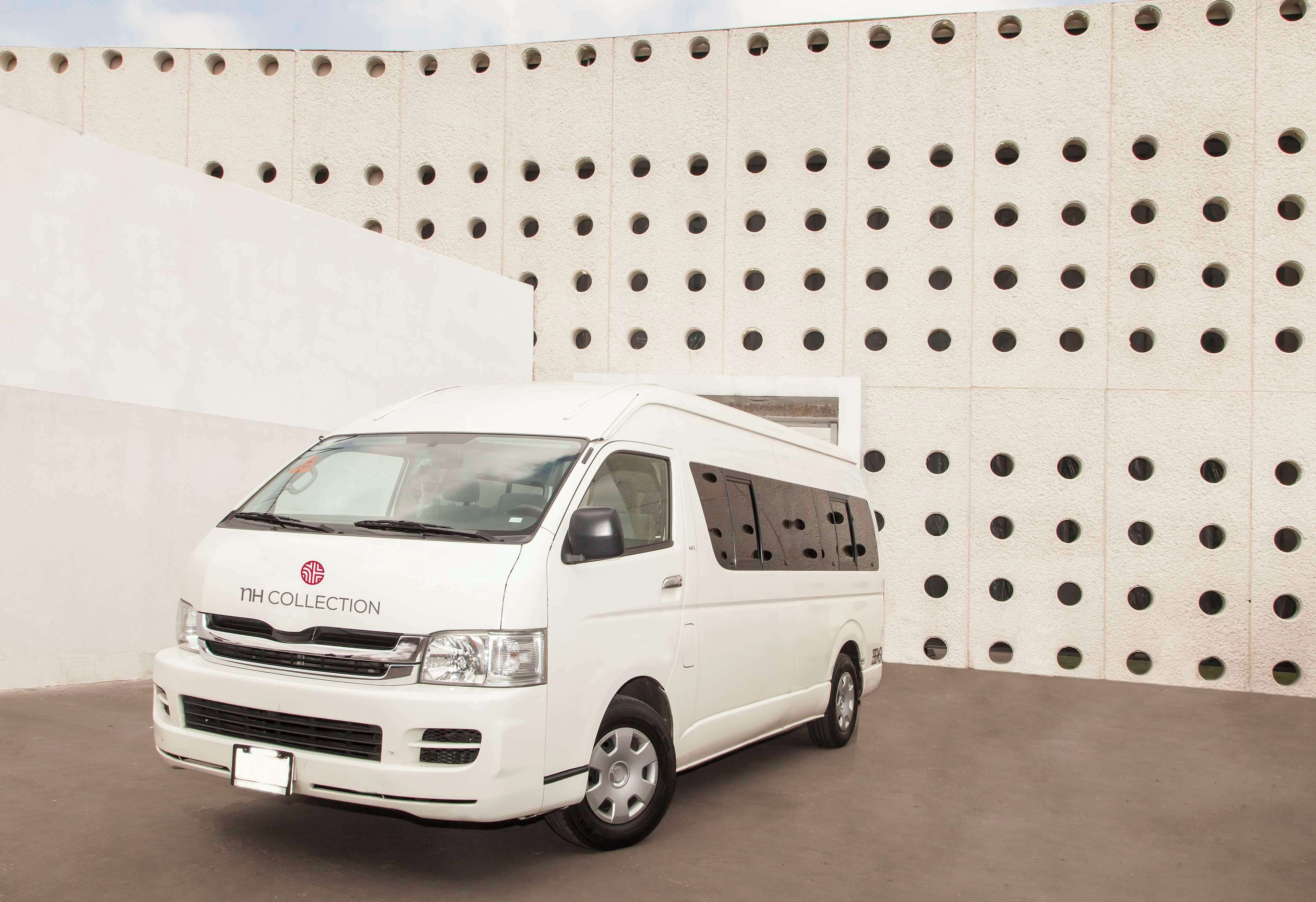 Una camioneta blanca estacionada frente a un muro con una cuadrícula de agujeros.