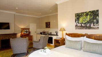 Een hotelkamer met een bed, bureau, stoel, televisie, schilderij en een keukenhoek.
