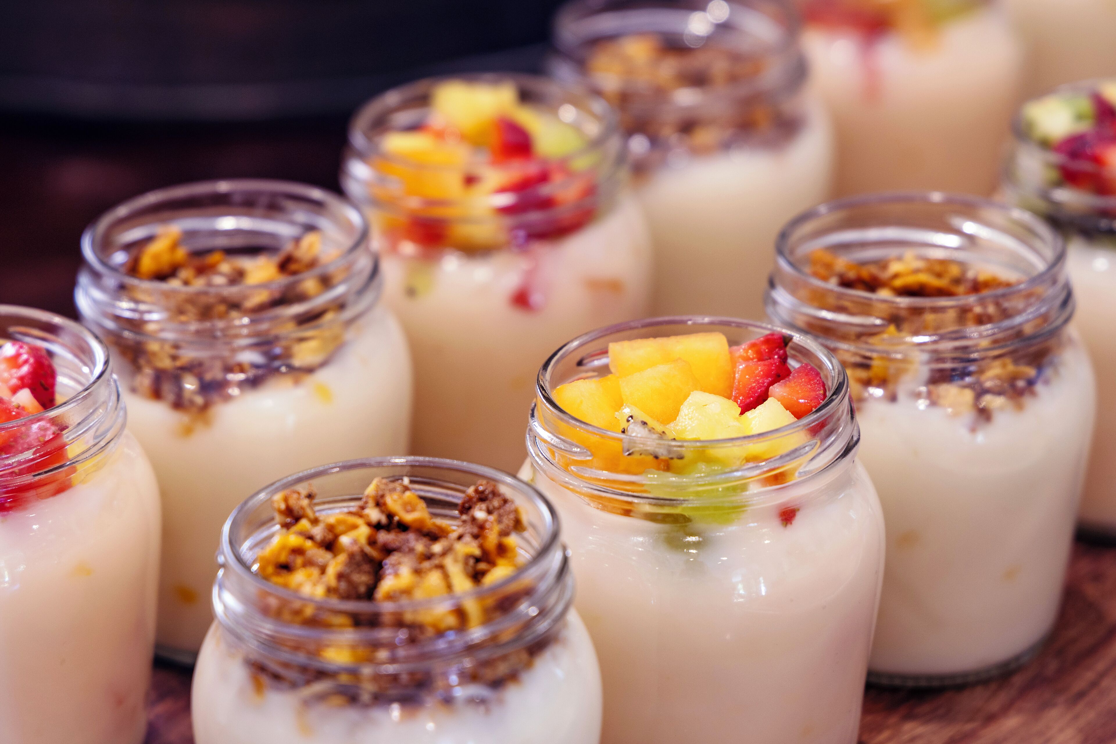Diversos postres en frascos de vidrio, algunos cubiertos con fruta y granola.