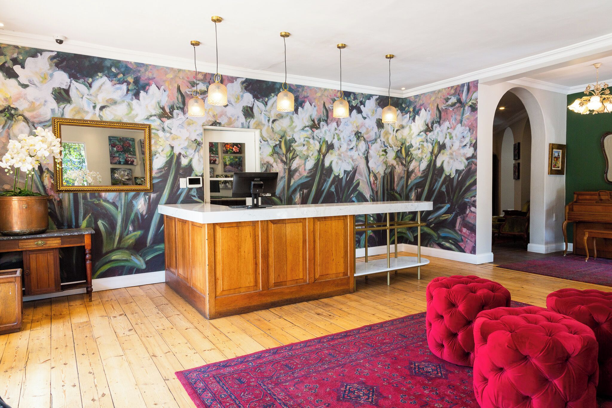 Una cocina con una isla de madera, un gran mural floral y un otoman rojo.