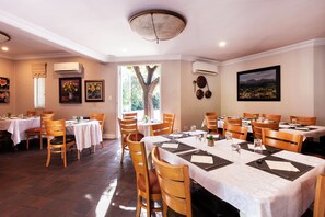 Un comedor con varias mesas y sillas, dispuesto en un espacio amplio.