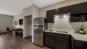 A modern kitchen with dark cabinets, a stainless steel refrigerator, a microwave, and a coffee maker. - Best Western Plus Bowie Inn & Suites (Bowie)