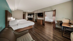 A modern hotel room with a bed, a desk, a chair, a TV, and a kitchenette. - Best Western Plus Bowie Inn & Suites (Bowie)
