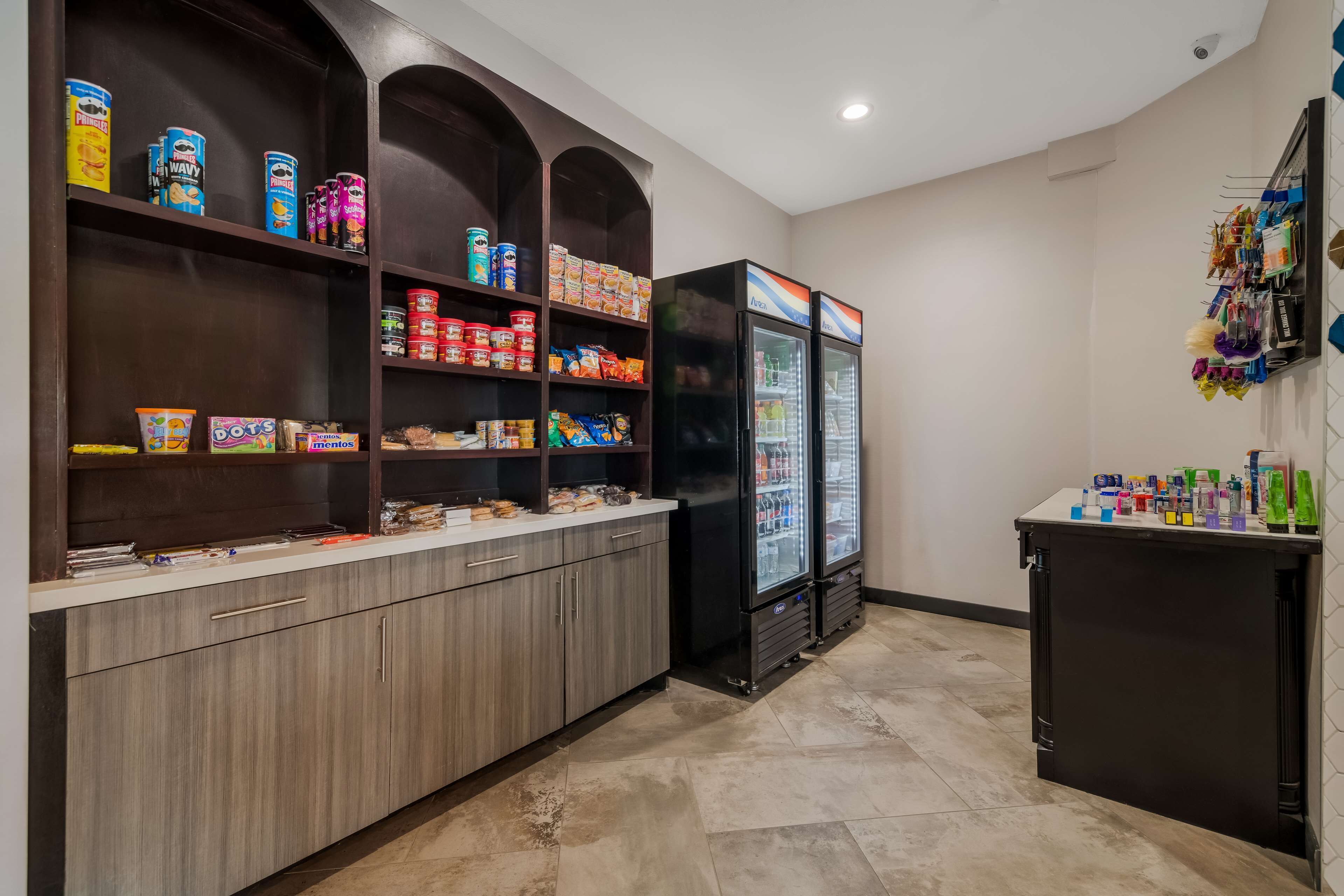 A kitchenette with shelves stocked with snacks, a refrigerator, and a small counter with condiments.