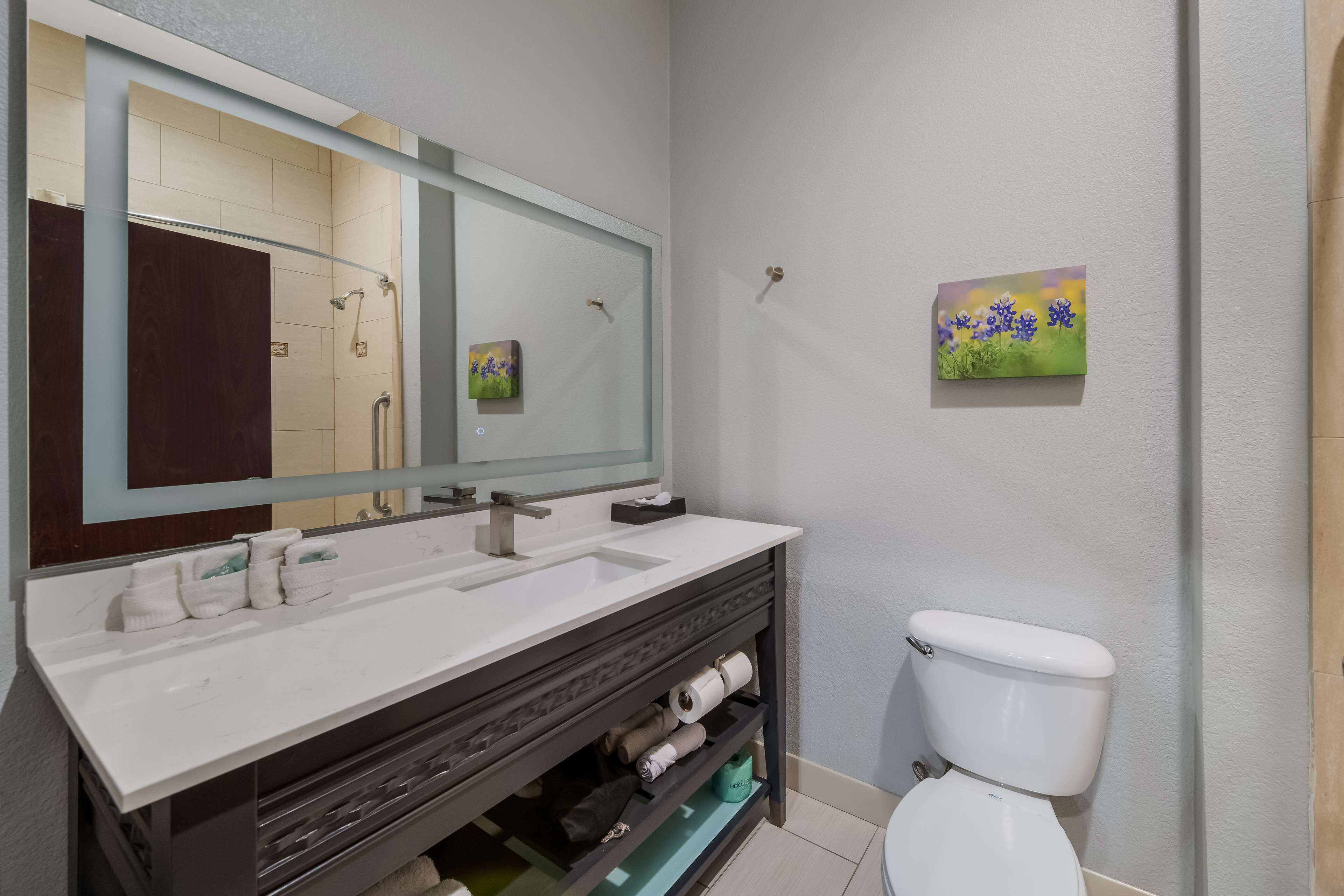 A bathroom with a white sink, dark vanity, and a toilet.
