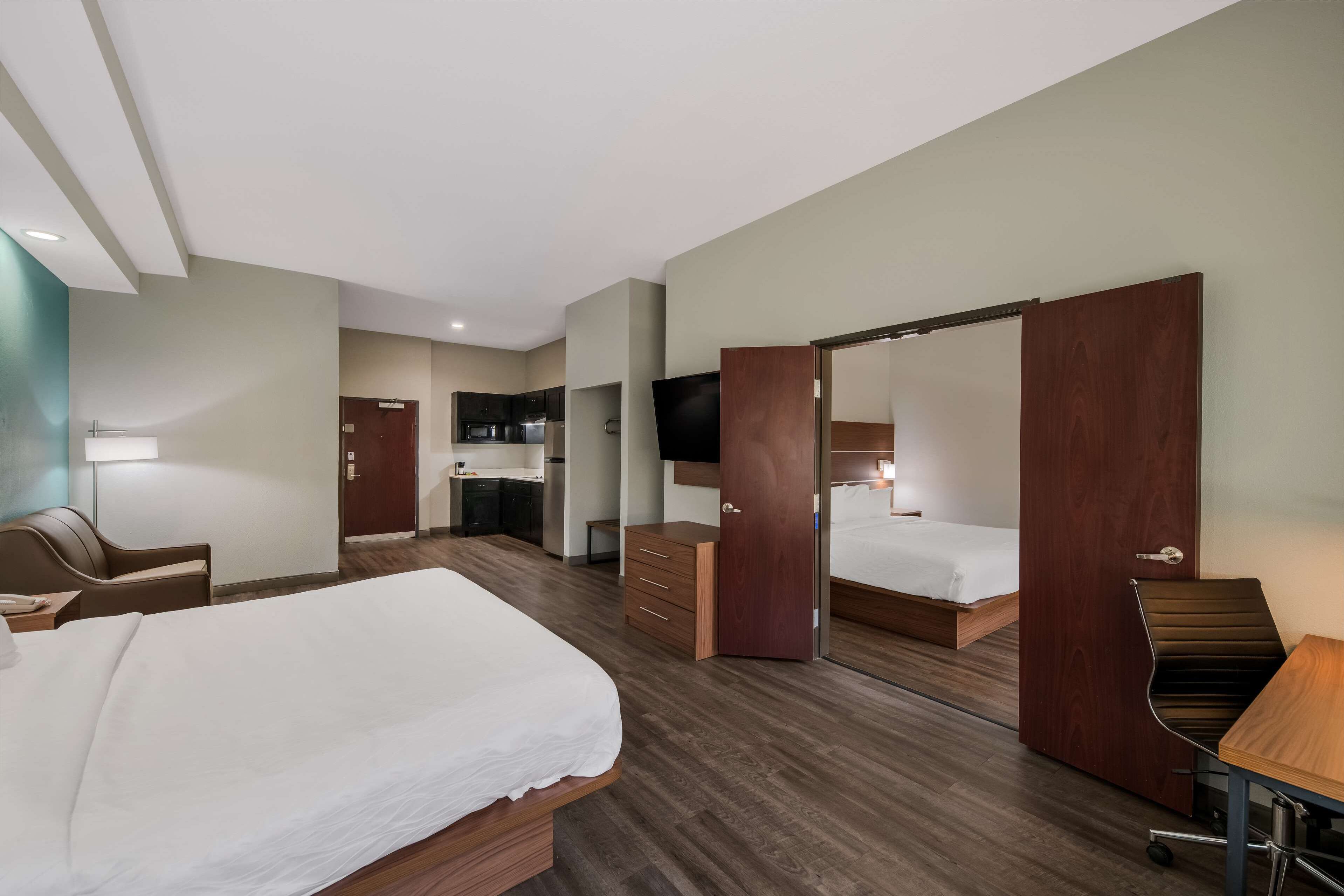 Ein Hotelzimmer mit Bett, Schreibtisch, Stuhl, Kleiderschrank und Fernseher.