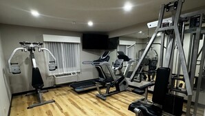 A gym with exercise equipment, a television, and a window with curtains. - Days Inn by Wyndham Lincoln, IL/Route 66 (Lincoln)