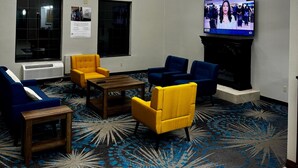 A hotel lobby with a large TV, seating area, and decorative ceiling light. - Days Inn by Wyndham Lincoln, IL/Route 66 (Lincoln)
