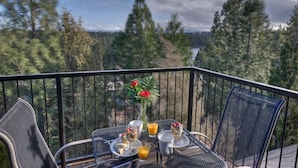 Un balcón con una mesa dispuesta para el desayuno, con vista a una zona boscosa.