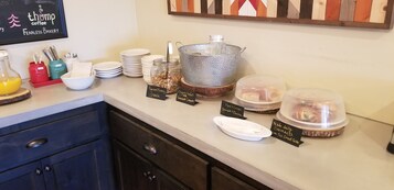 A breakfast buffet with labeled food items like granola, yogurt parfait, and croissants.
