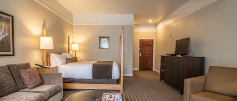 A hotel room with a bed, a sofa, a coffee table, a TV, and a wooden ceiling.