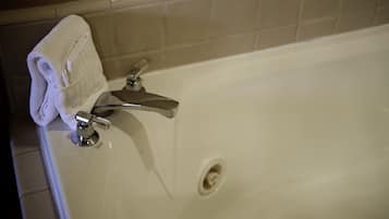 A white bathtub with a chrome faucet and a towel on the side.