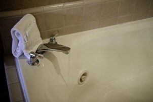 A white bathtub with a chrome faucet and a towel on the side.