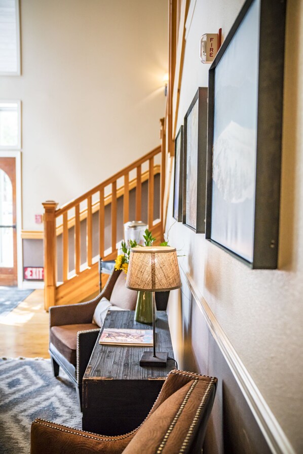 A hallway with a wooden staircase, a framed picture, a lamp, and a sofa.