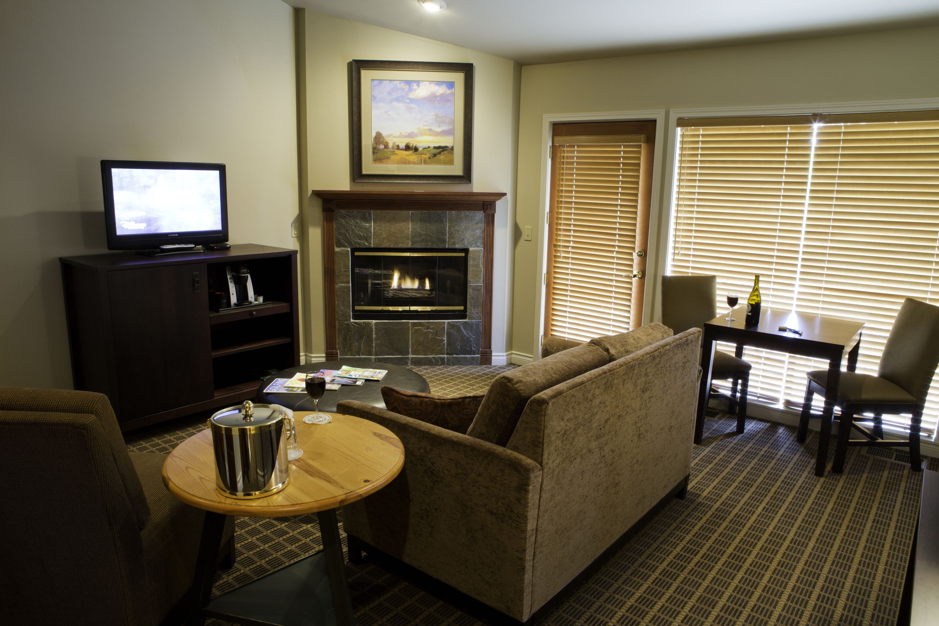 A living room with a fireplace, a television, a sofa, and a dining area with a table and chairs.