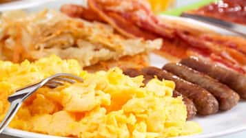 A plate of scrambled eggs, sausages, and bacon.