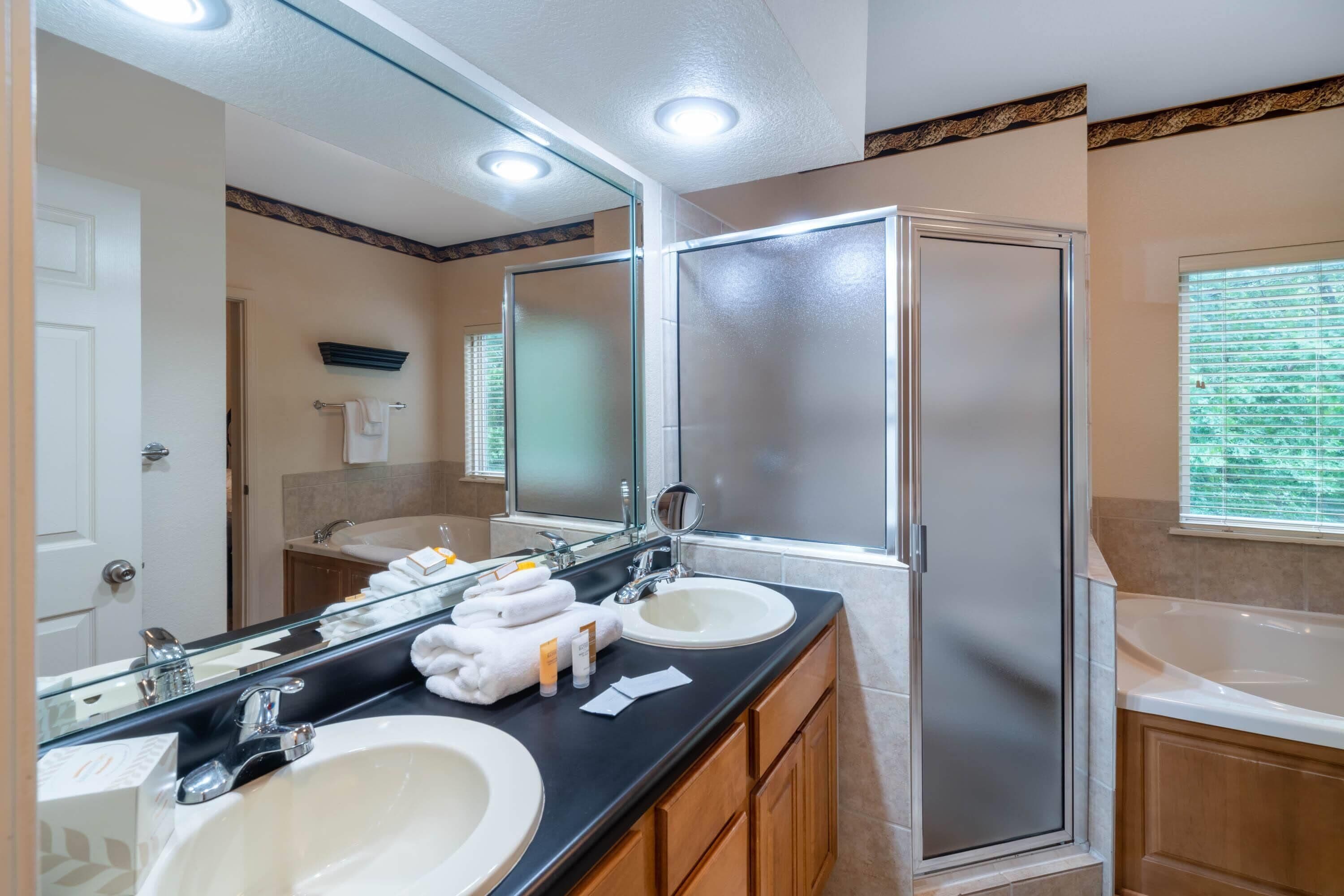 A bathroom with two sinks, a large mirror, and a shower enclosure.