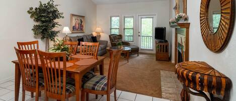 A dining area with a wooden table and chairs, a ceiling fan, and a large mirror on the wall.