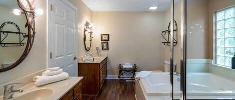 A bathroom with a large mirror, vanity with a sink, a bathtub, and a shower area.