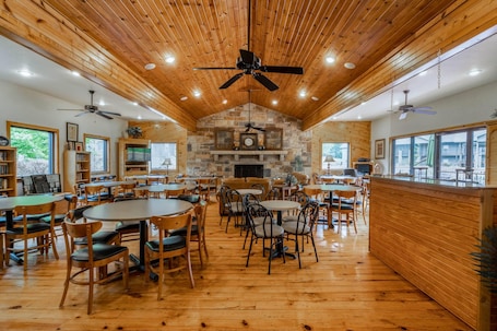 A spacious dining area with wooden flooring and ceiling fans, surrounded by bookshelves and large windows.