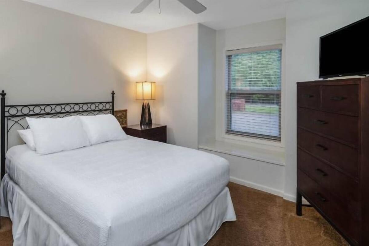 Une chambre à coucher avec un lit, des lampes de chevet, une commode et un téléviseur.