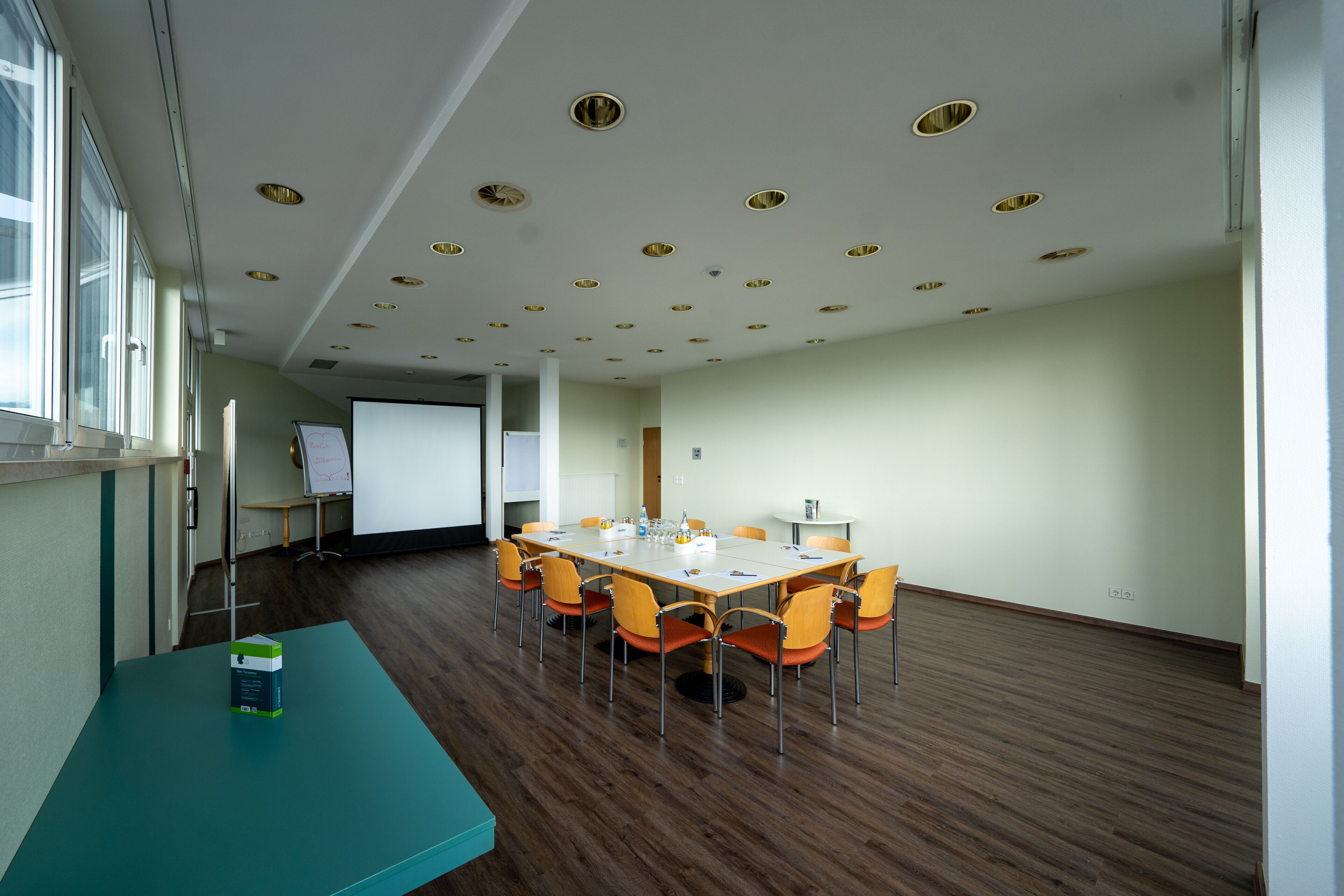 A conference room with a long table, chairs, a projector screen, and a whiteboard.