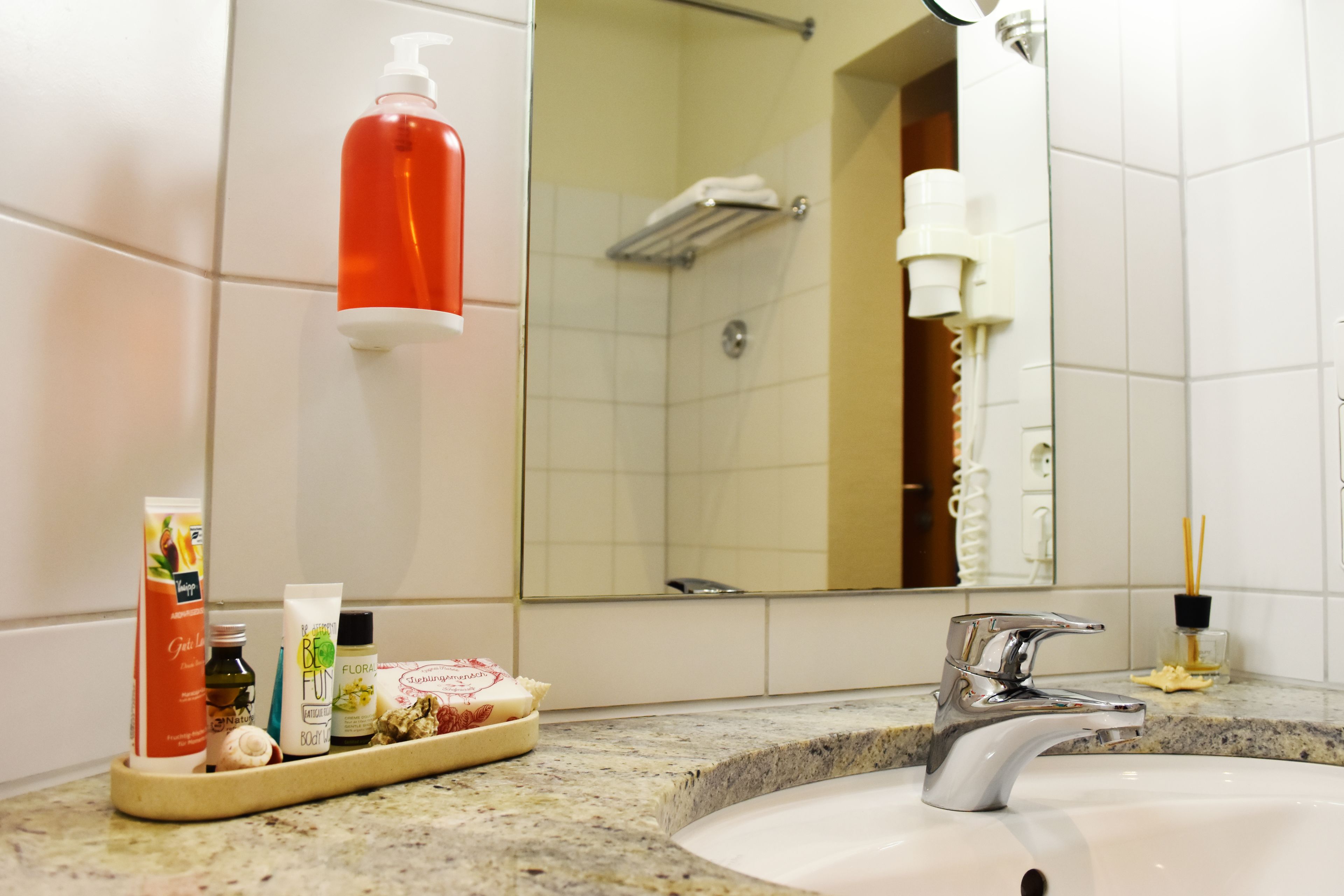 Een badkamer met een wastafel, spiegel, toiletartikelen en een douche.