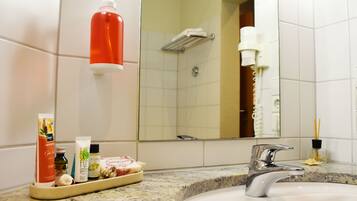 Een badkamer met een wastafel, spiegel, toiletartikelen en een douche.