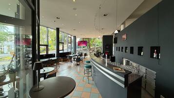 Un restaurante moderno con barra, ventanas amplias y suelo de baldosas.