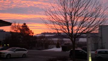A sunset with a tree in the foreground and a building in the background.