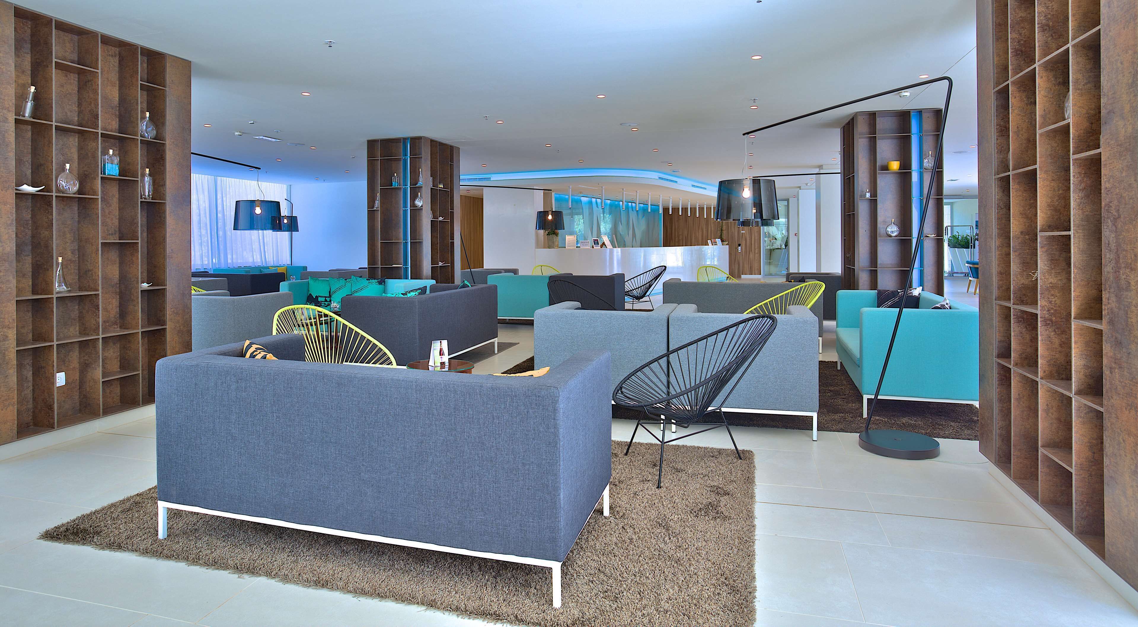 A modern living room with grey sofas, a black chair, and a blue accent wall.