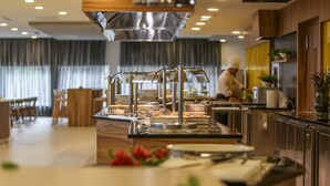 Cocina moderna con electrodomésticos de acero inoxidable, un sistema tipo buffet y un chef preparando comida.