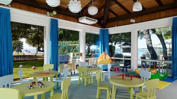 Children can play and dine in this vibrant space with tables, chairs, and a play area visible through large windows.