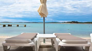 På stranden, strandtelt (mot et tillegg), solsenger og parasoller