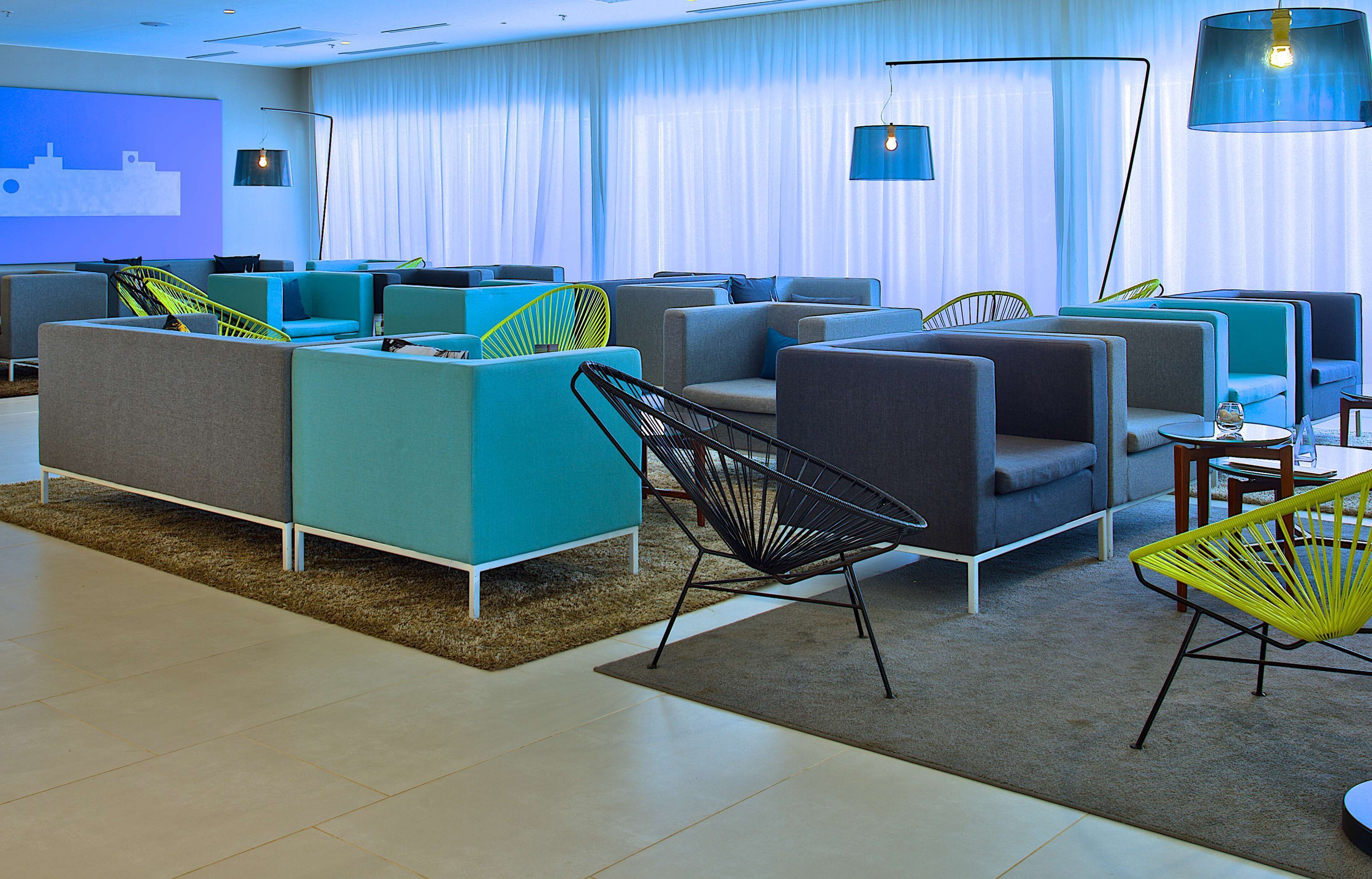 A modern lounge area with multiple seating options, including sofas and chairs, arranged in a spacious layout.
