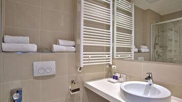 A modern bathroom with a white sink, a towel rack, and a mirror.