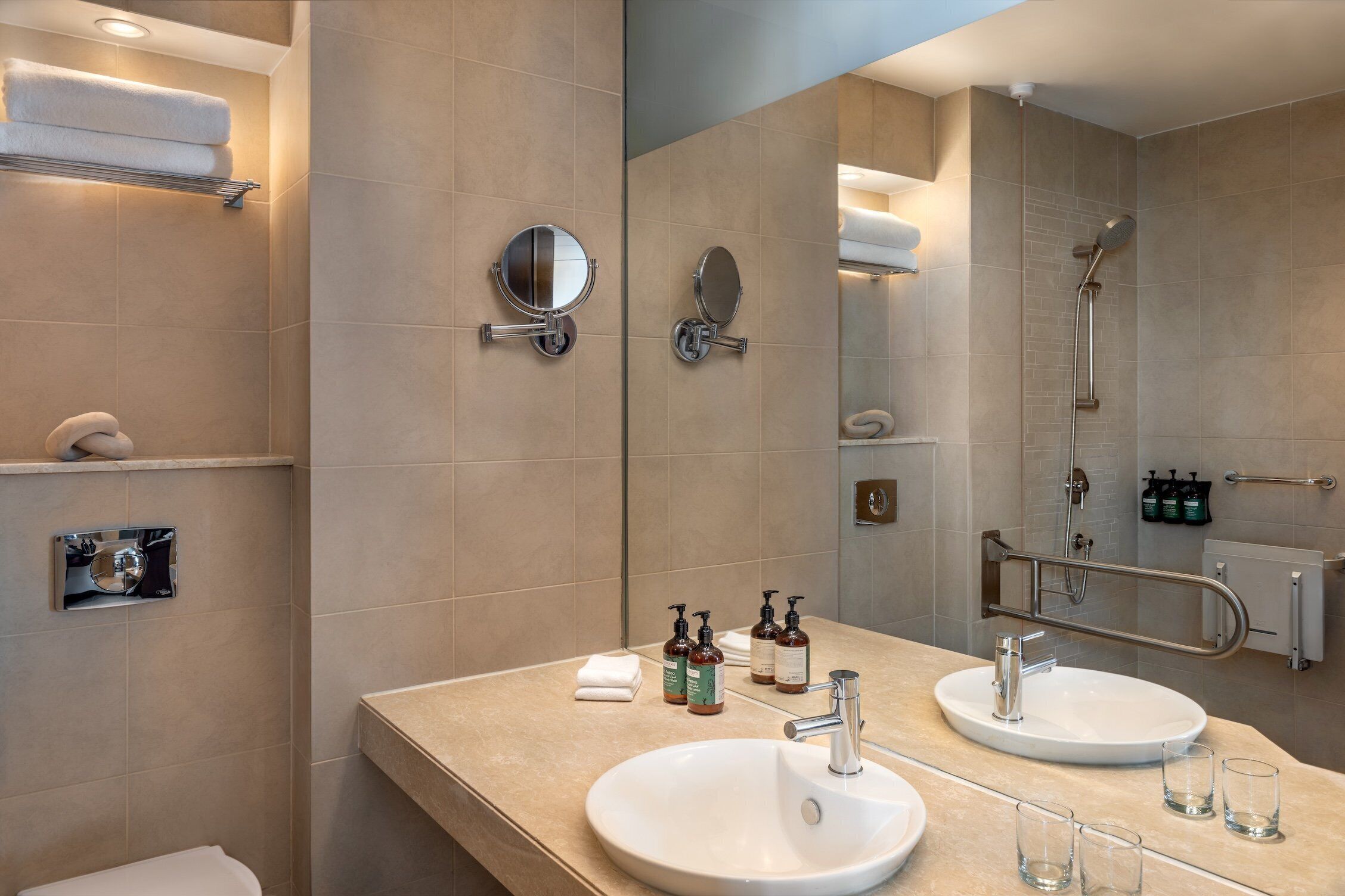 A modern bathroom with two sinks, a large mirror, and a shower.