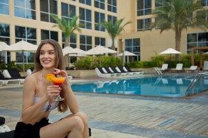 Una piscina al aire libre, sombrillas, sillones reclinables de piscina