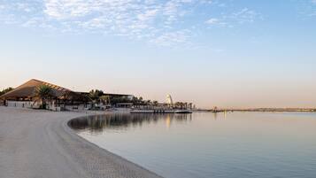 A beach with a large building, a calm sea, and a clear sky.