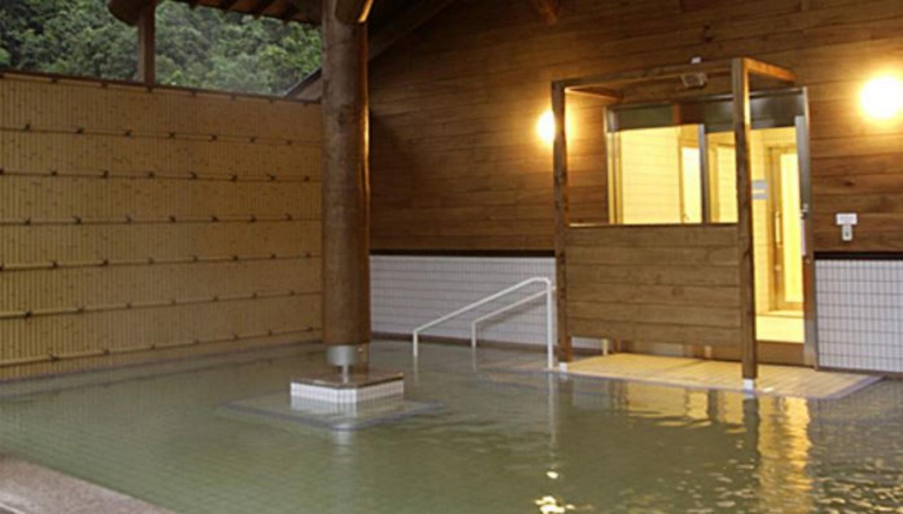 A wooden building with a pool area, including a glass-enclosed section and a tiled walkway.