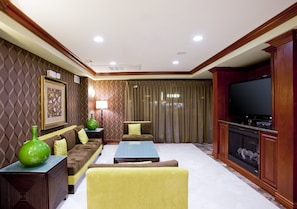 Una sala de estar con sofá, sillones, una mesa de centro, televisor y chimenea.