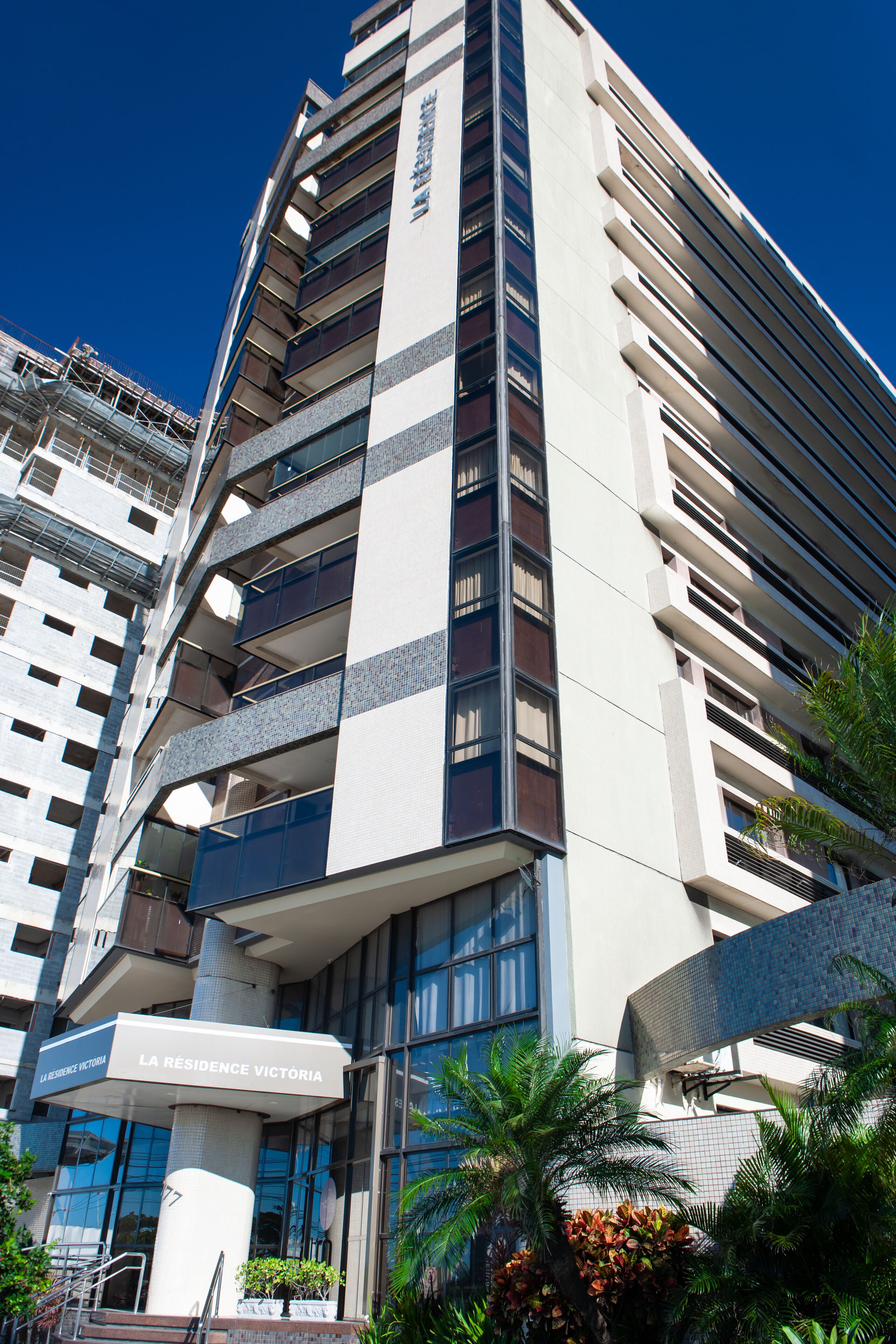 Et moderne hotel med flere etager, altaner og en klar himmel.