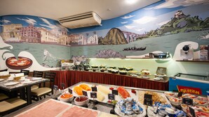 Een buffet met diverse gerechtjes en een muurschildering van een kustlandschap.