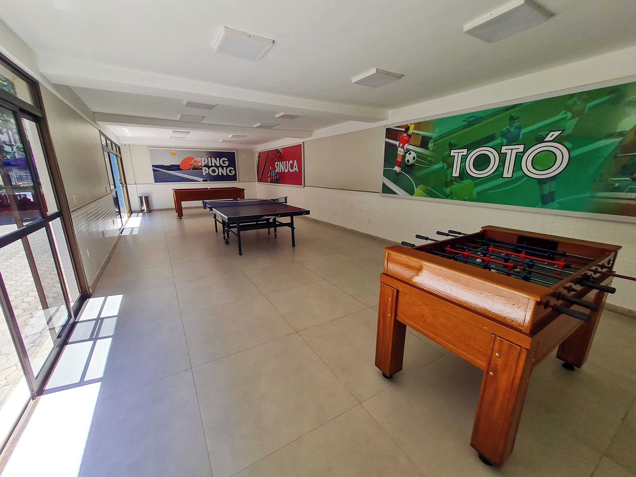 A recreational area with ping pong tables, a foosball table, and a billiards table.